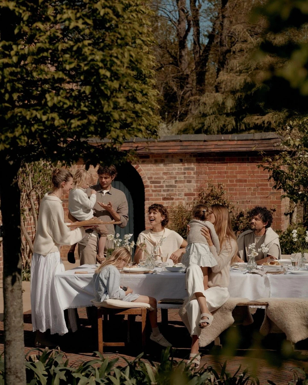 Familie mit Kindern an einer gedeckten Tafel im sonnigen Garten